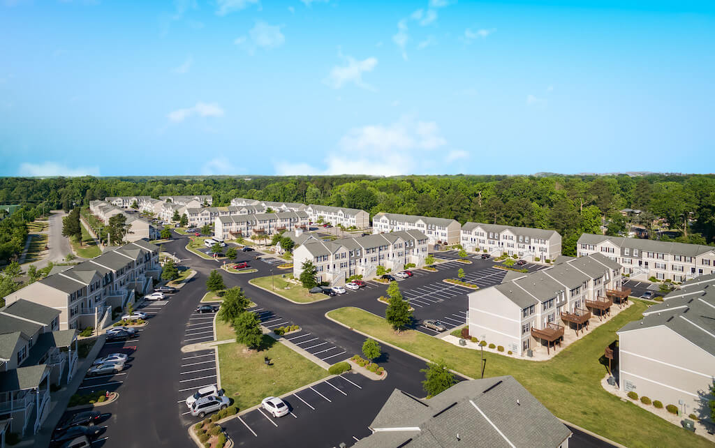 Birds eye view of apartment community with trees in the horizon.