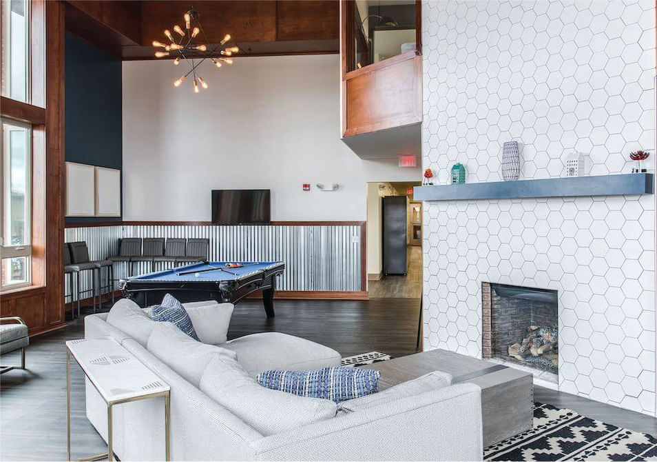 clubhouse with pool table and couch facing white honeycomb tile fireplace
