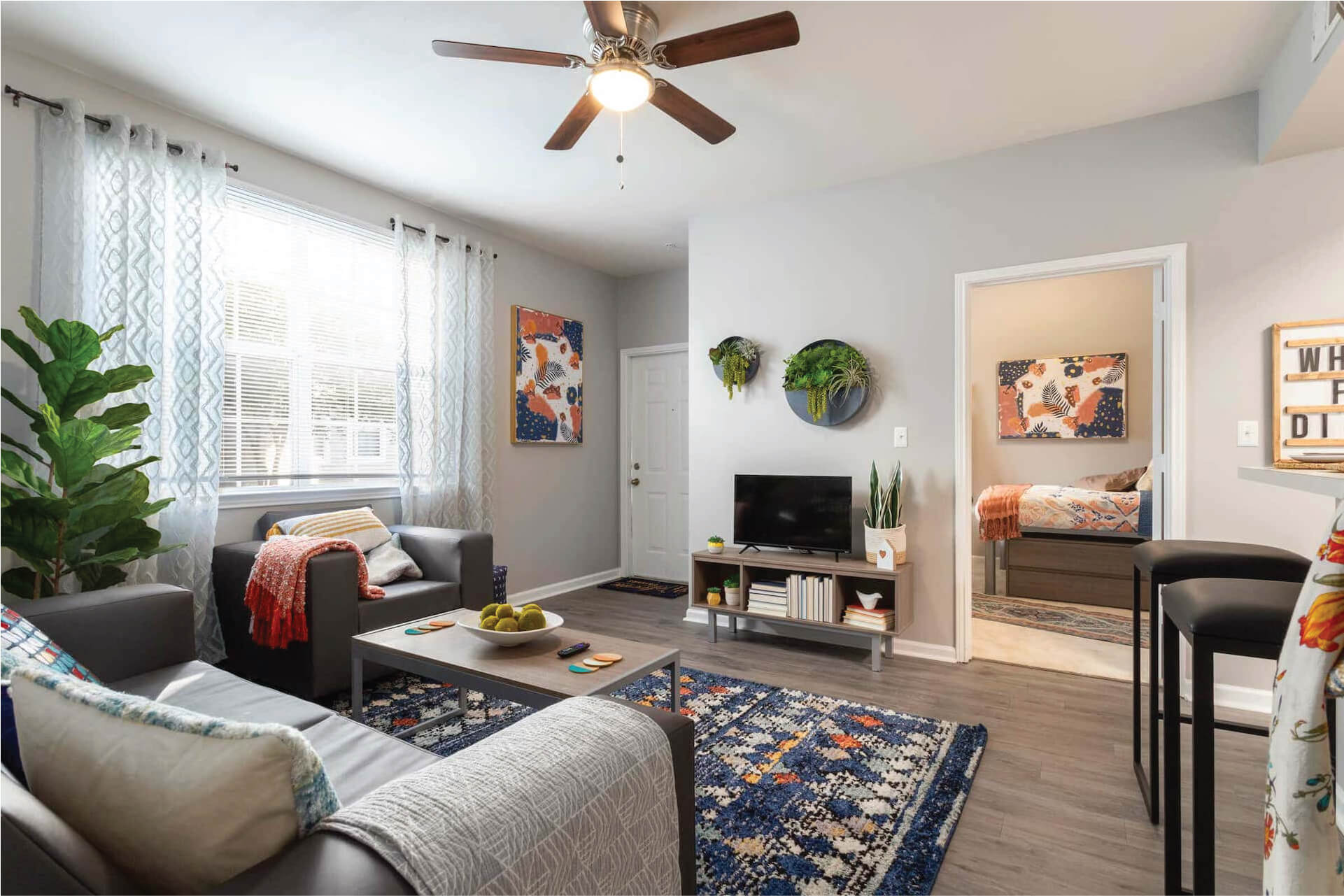 model living room with modern furniture, television, and door open to a bedroom.